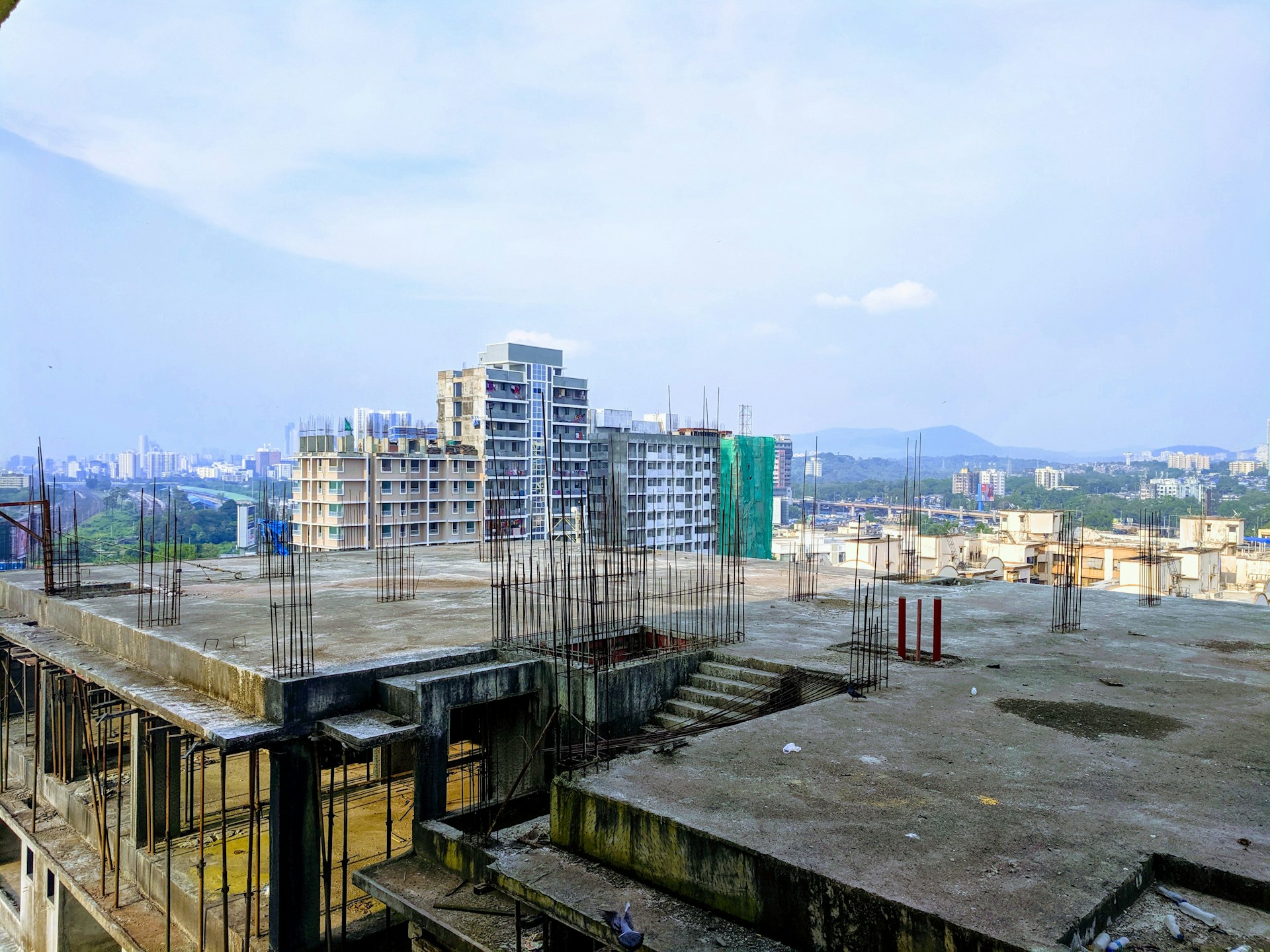 Architect reviewing blueprints on a construction site with Colombian cityscape in the background