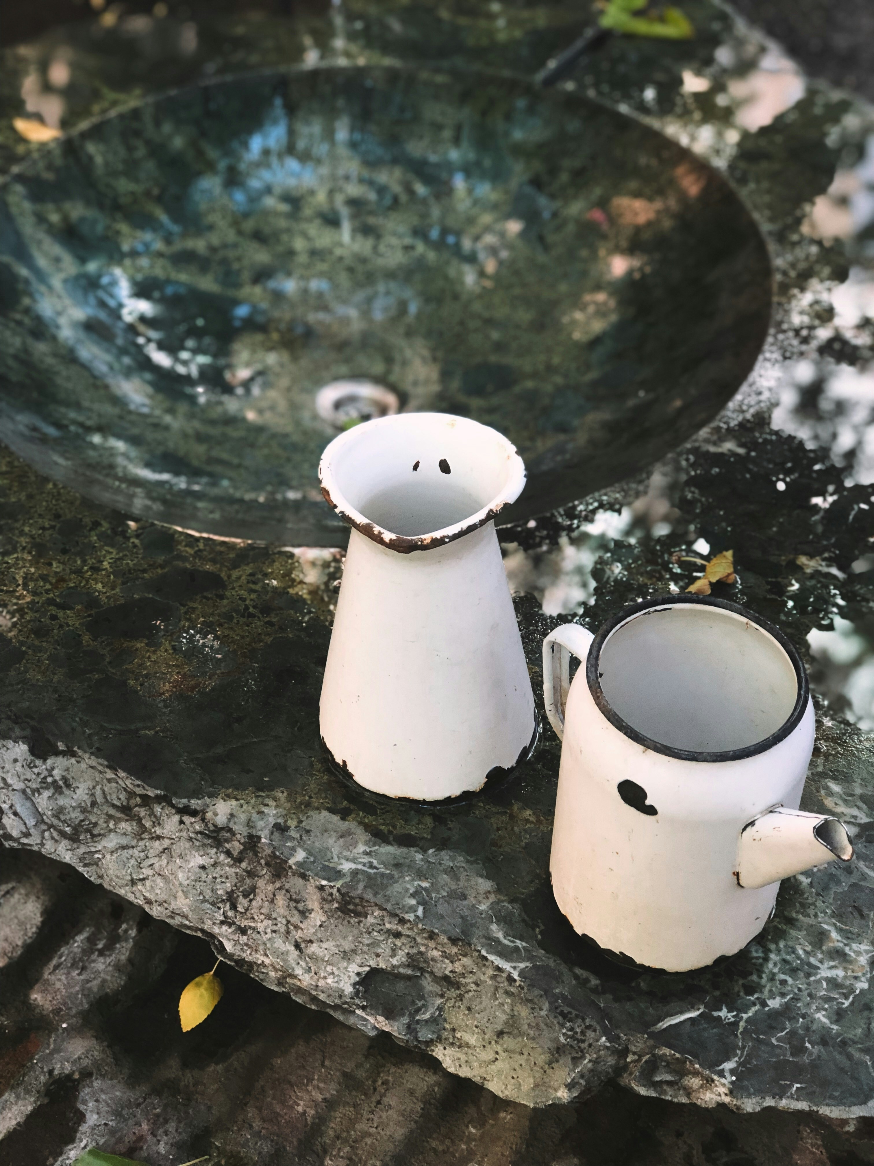 two white enamel pitchers beside a sink