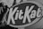 Close-up view of the Kit Kat logo surrounded by a black and white background. The bold letters are prominently displayed, creating a striking contrast against the darker surrounding elements.