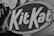 Close-up view of the Kit Kat logo surrounded by a black and white background. The bold letters are prominently displayed, creating a striking contrast against the darker surrounding elements.
