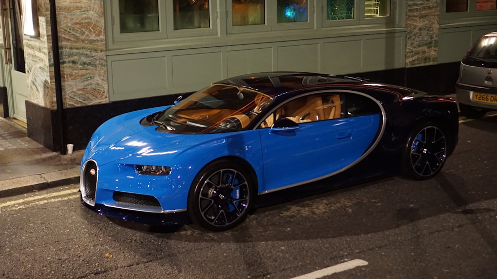 A sleek, midnight blue luxury sports car gleaming under city lights.