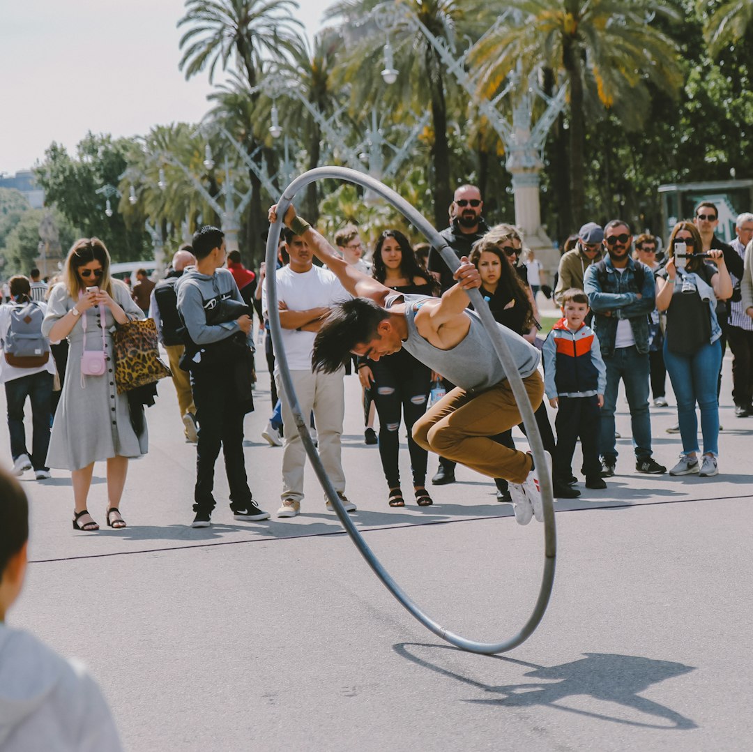 A street artist performing a stunt with a giant hula hoop in front of a crowd