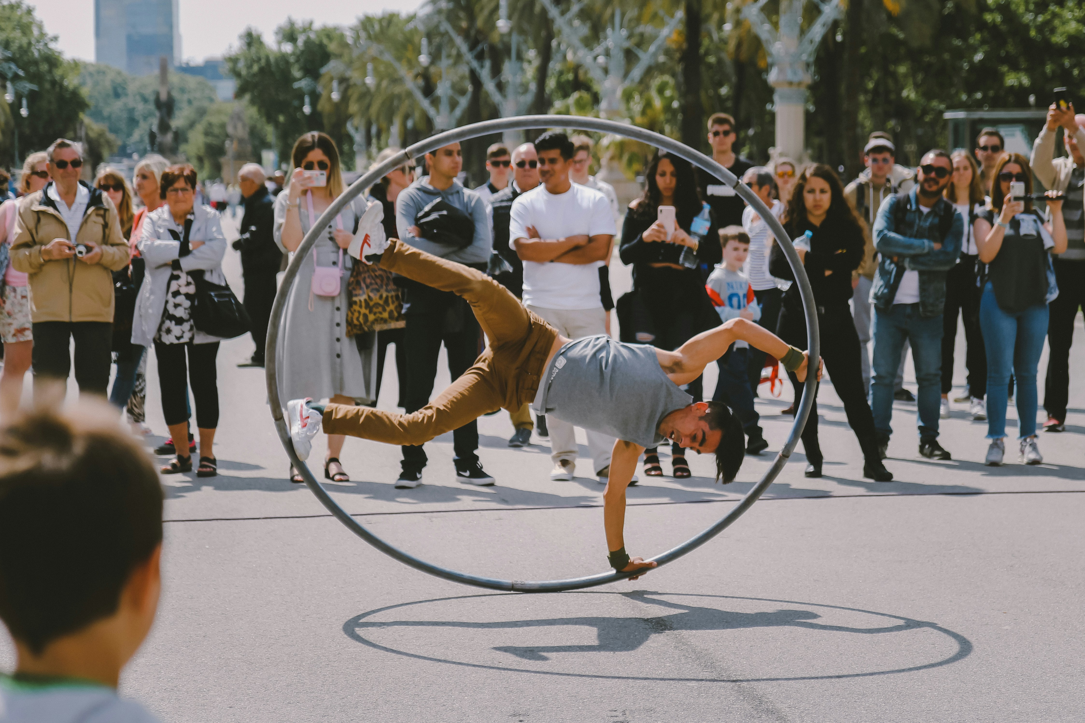 A street artist performing a stunt with a giant hula hoop in front of a crowd
