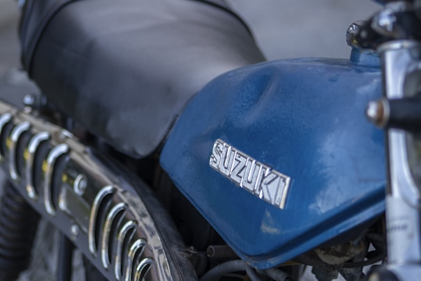 Close-up of the Suzuki logo on the fuel tank of a shiny white two-wheeler
