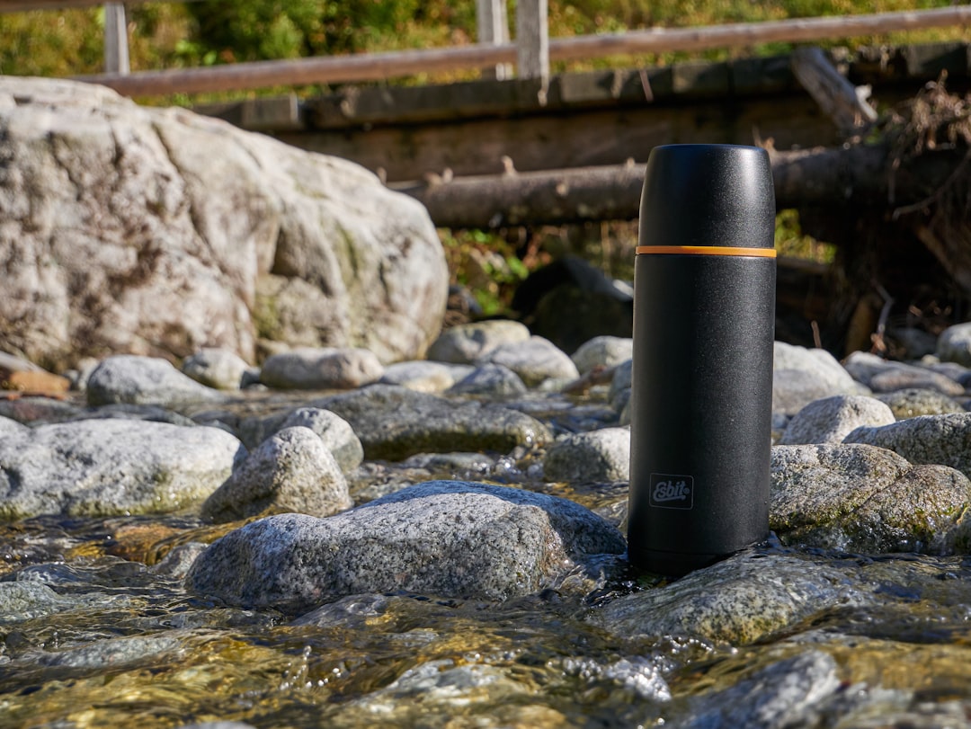 blue tumbler on rocks by bridge during daytime,