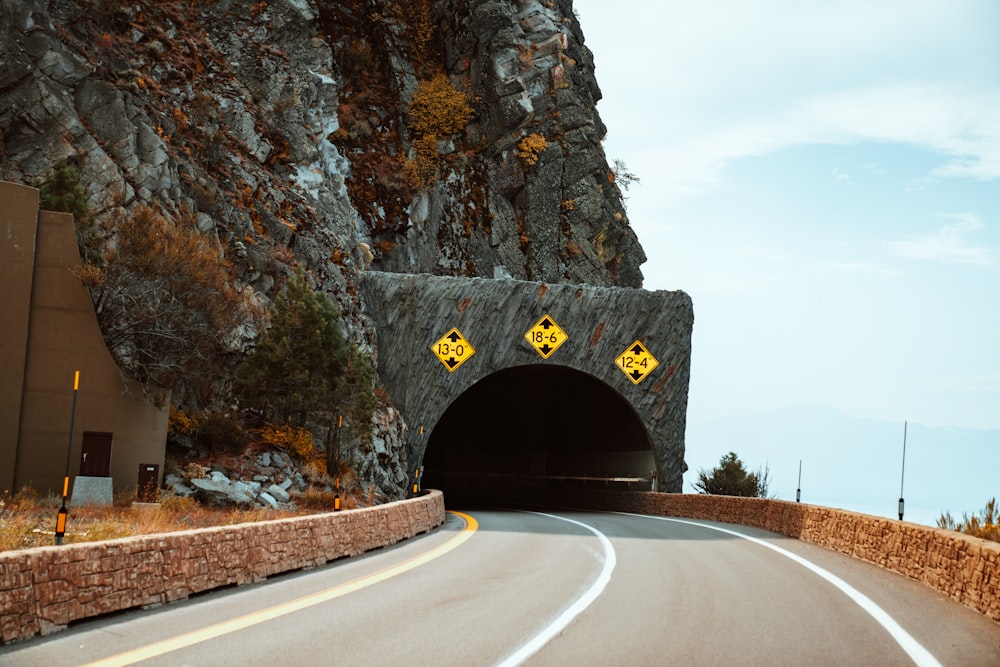 route sans véhicule circulant dans le tunnel sous un ciel blanc et bleu pendant la journée