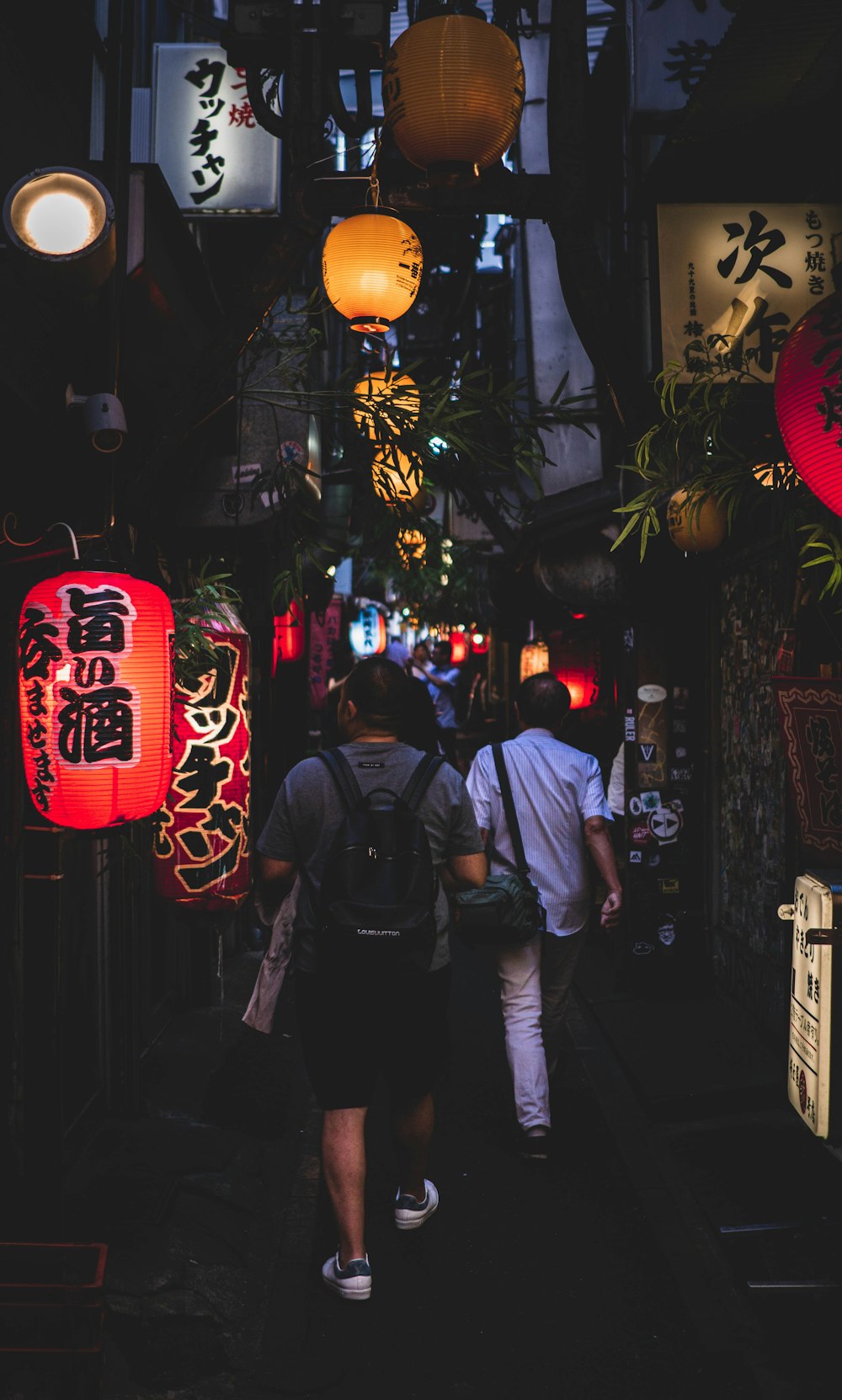 men walking along narrow street with hanging lanterns