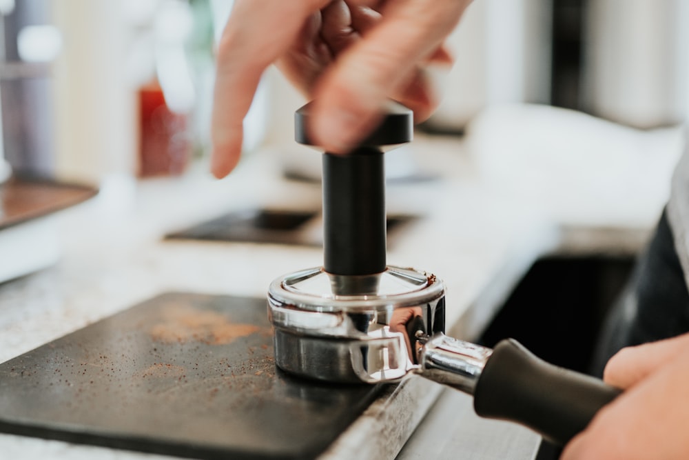 close-up photography of person holding black and gray metal hand tool