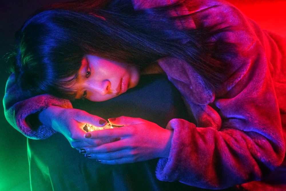 woman wearing red jacket holding lighted stone