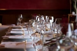 A beautifully set dining table with fine linen napkins and tablecloths in a softly lit restaurant.