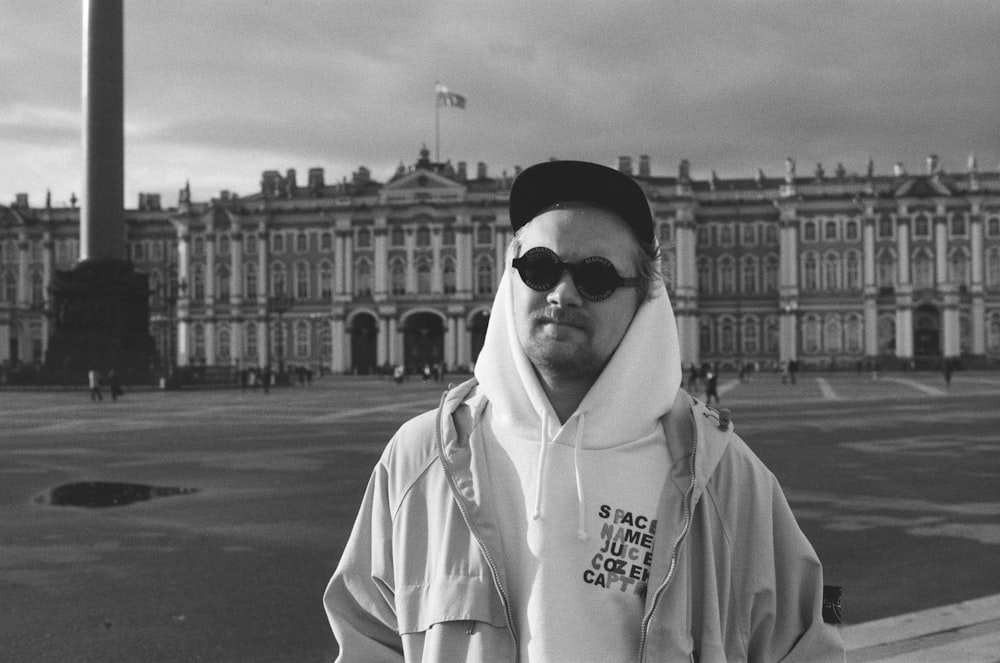 grayscale photography of man standing near Hermitage Museum in Russia