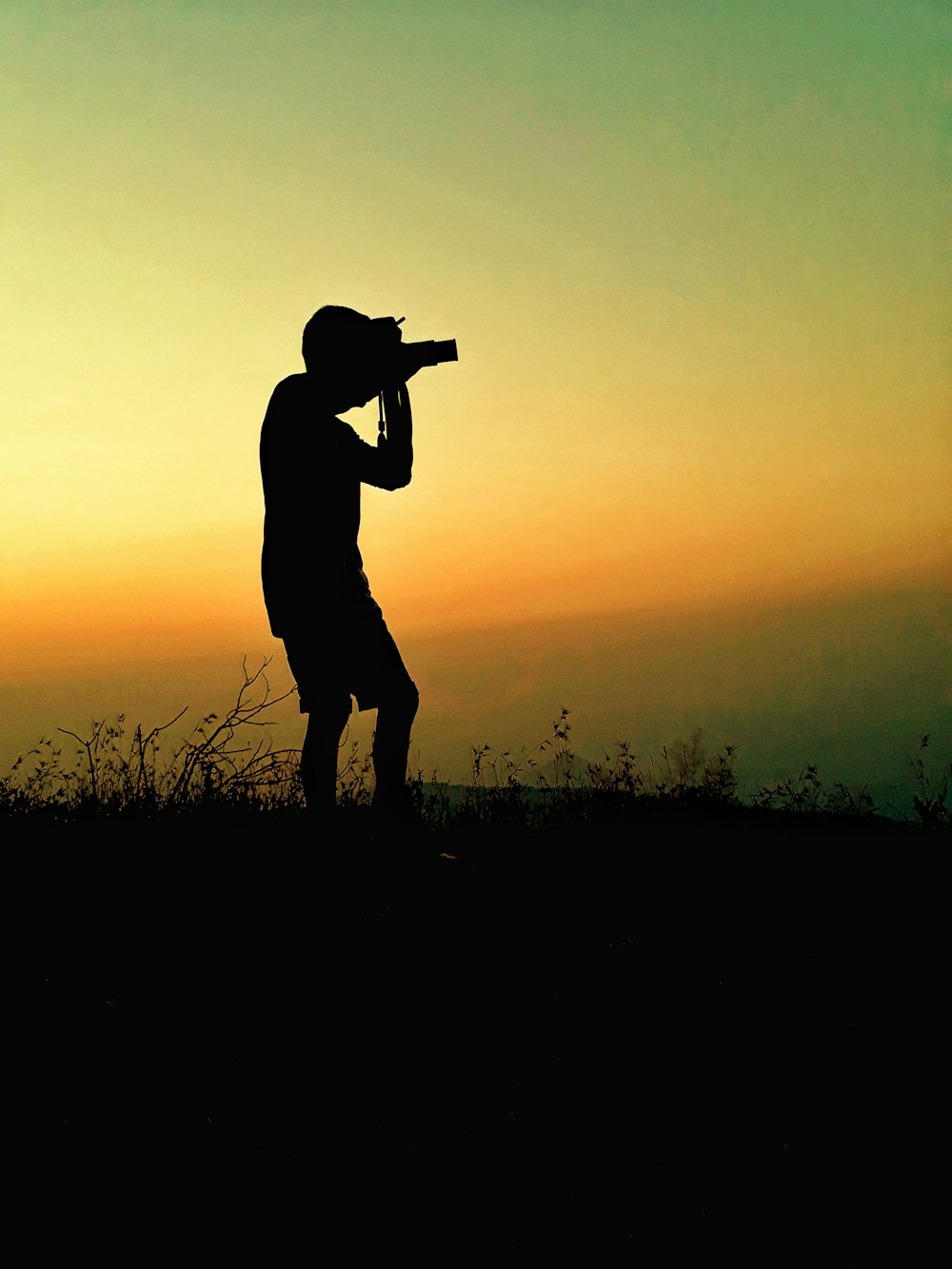silhouette photography of man taking picture using camera