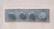 Four large metal bolts are embedded in a rectangular metal plate on a concrete wall. Each bolt has a round, flat head with a hexagonal base, showing signs of wear and tarnish.