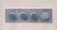 Four large metal bolts are embedded in a rectangular metal plate on a concrete wall. Each bolt has a round, flat head with a hexagonal base, showing signs of wear and tarnish.