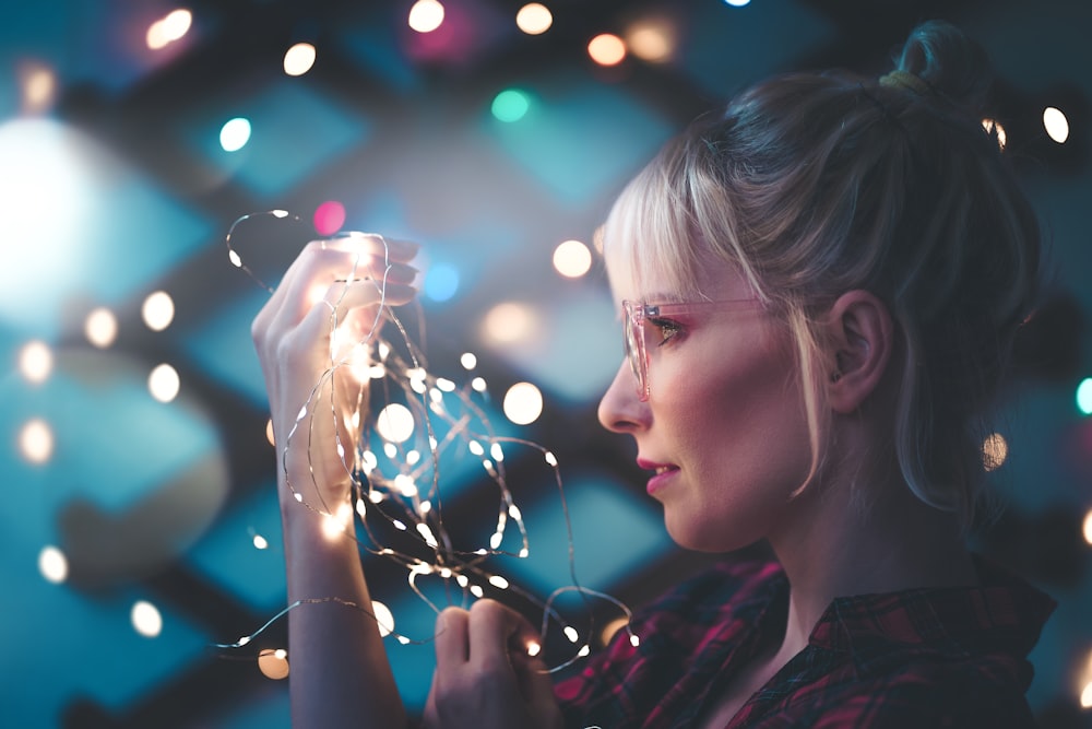 femme tenant des guirlandes lumineuses