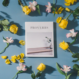 Proverbs book beside white and pink flowers