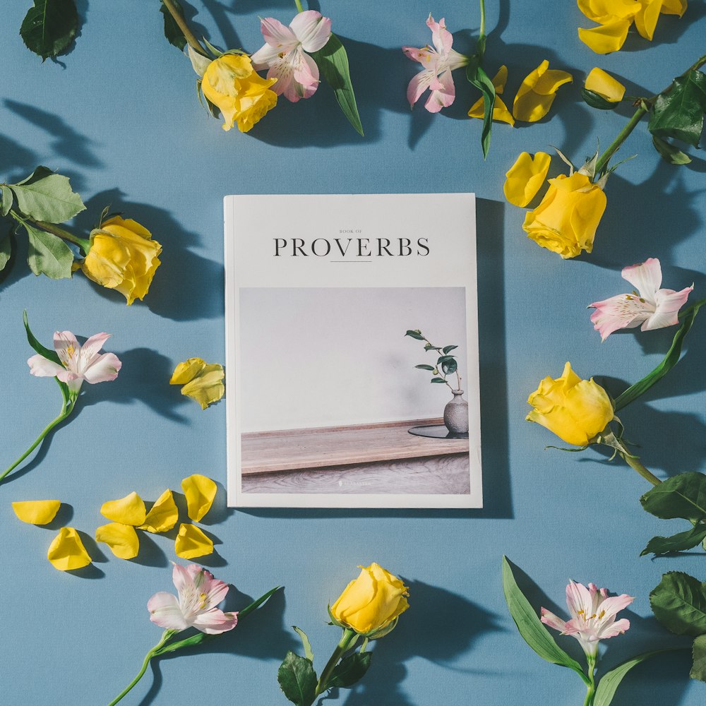 Libro di proverbi accanto ai fiori bianchi e rosa