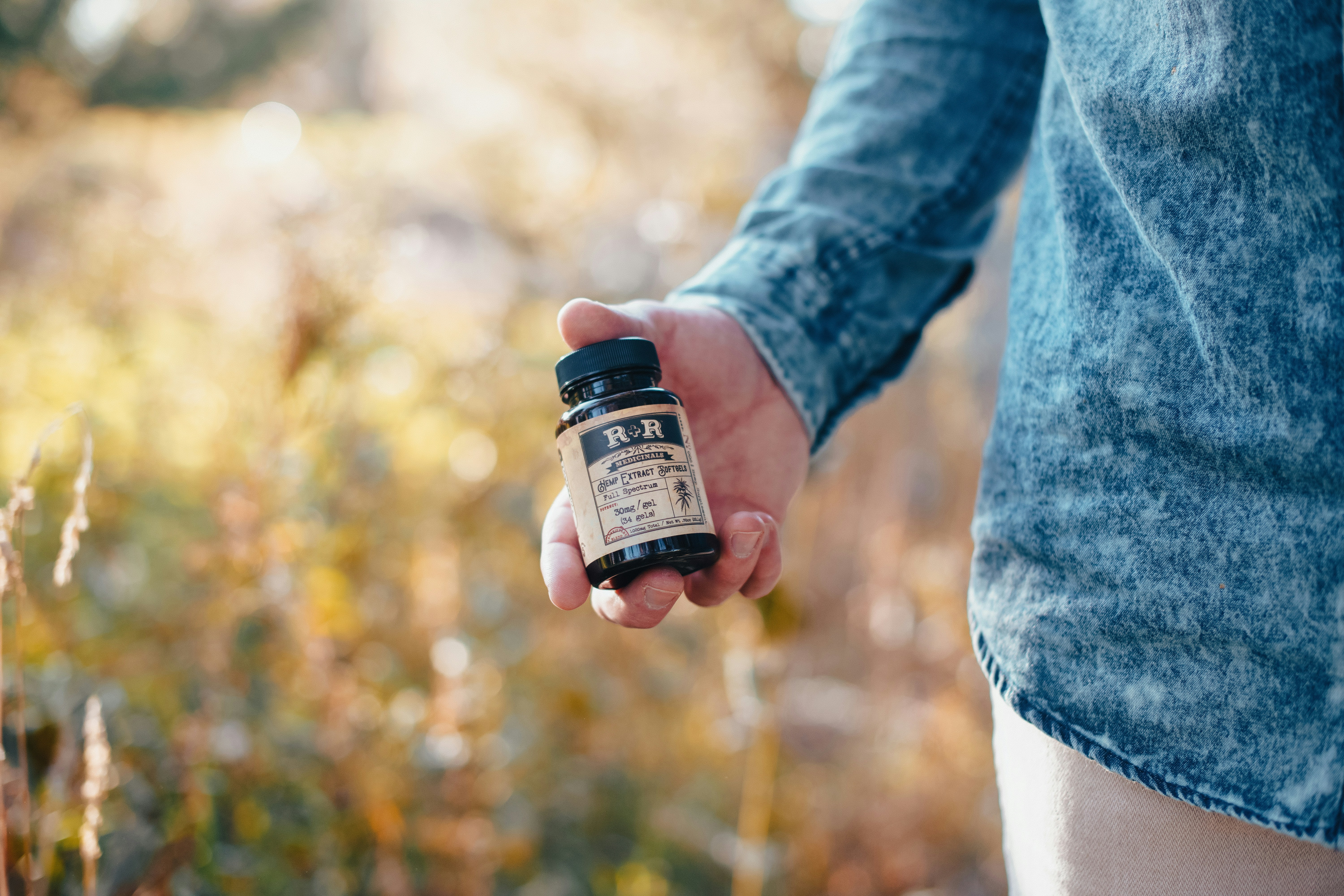 Colorado man holding hemp extract softgel bottle in a fall and autumn setting.