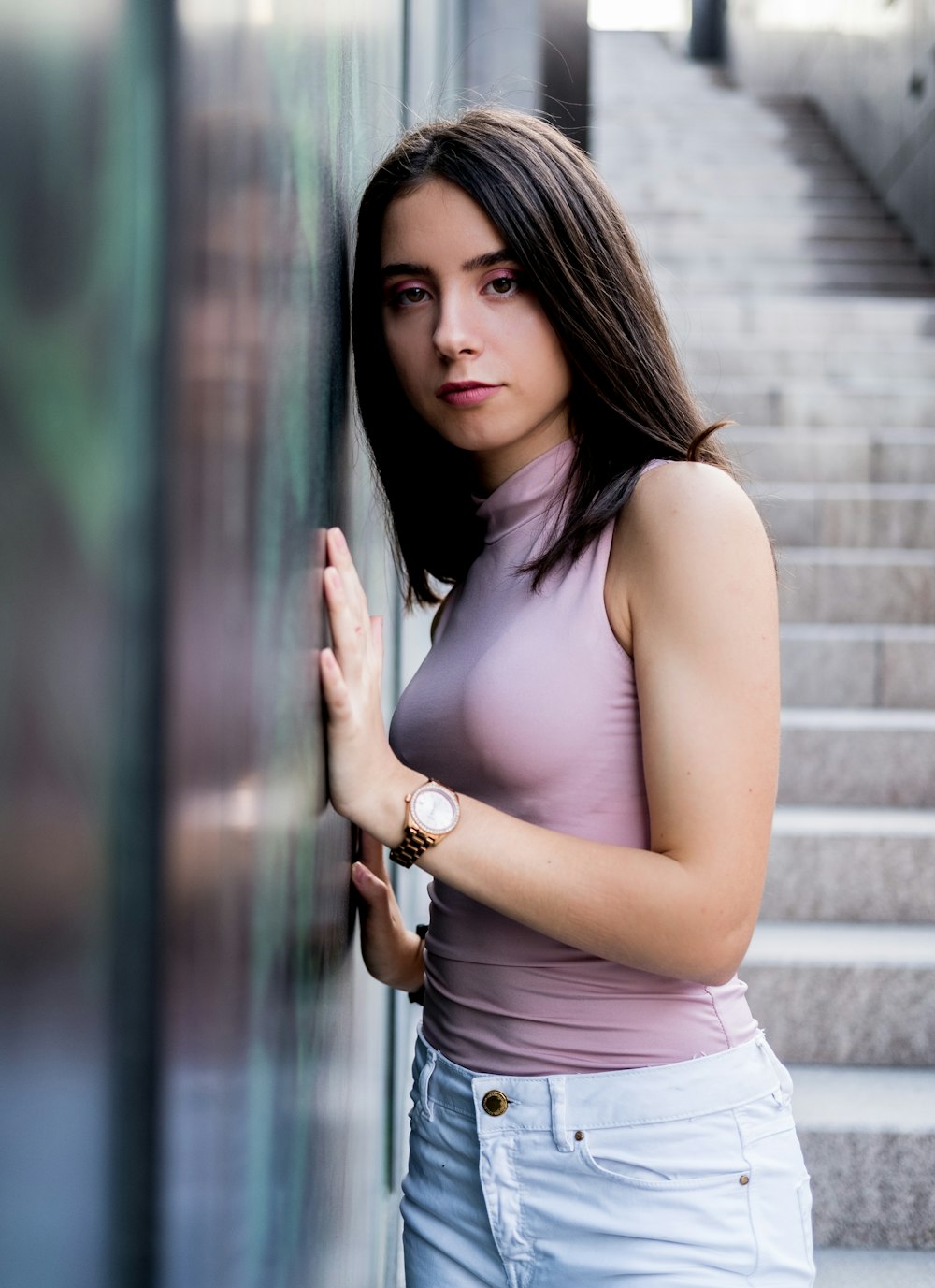 woman in pink sleeveless top and white bottoms standing outdoors