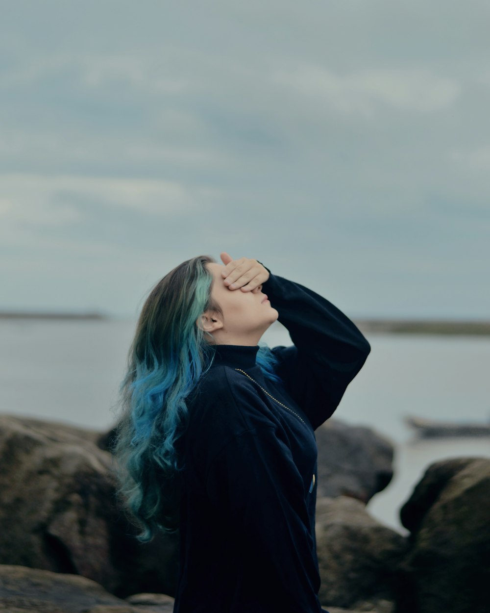 woman wearing black jacket covering her eyes