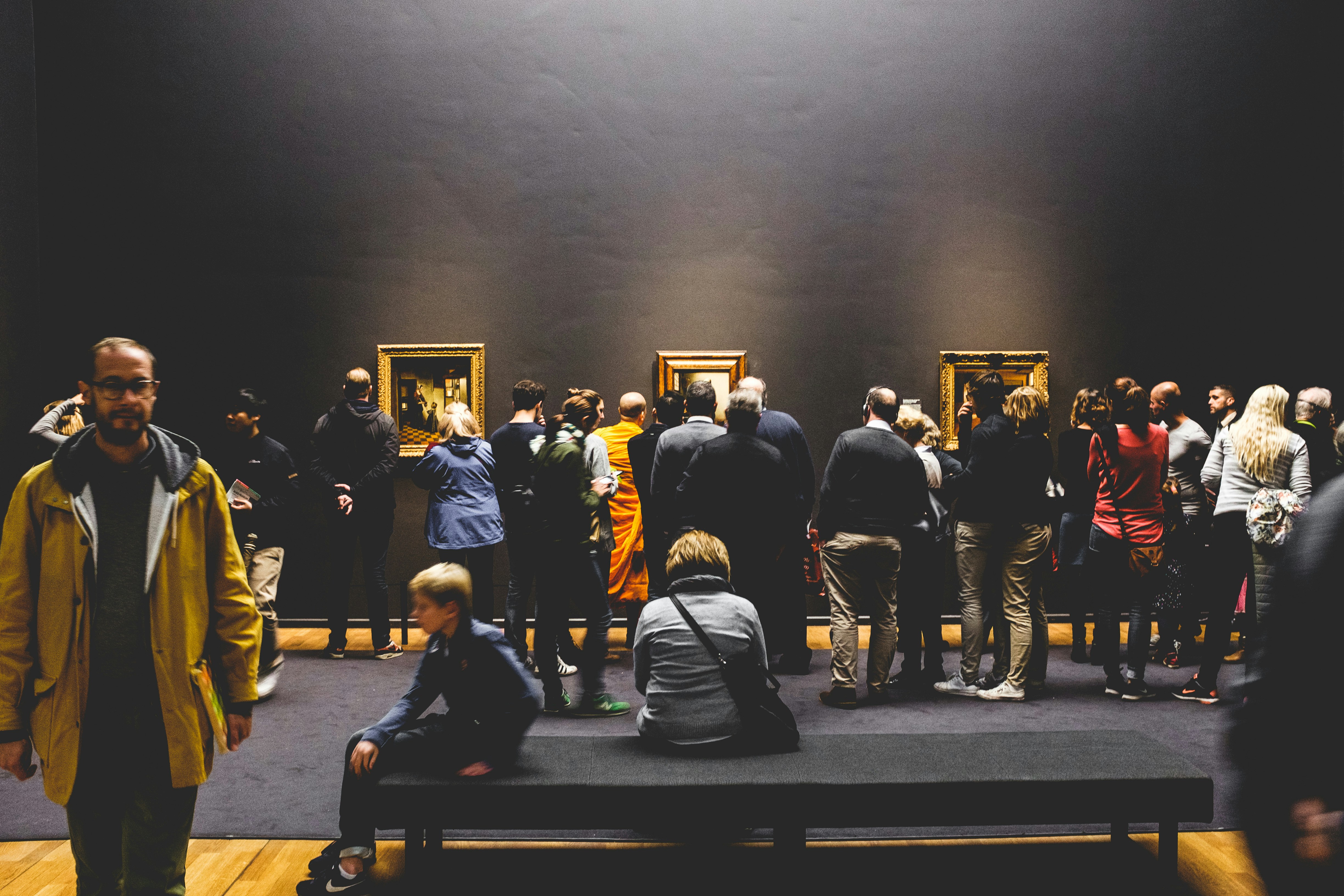 Galería de arte con pinturas enmarcadas en pared oscura, iluminación de spot puntual sobre obras