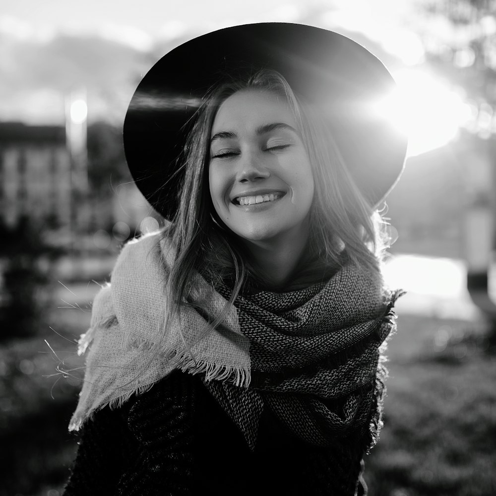 Foto en escala de grises de mujer con sombrero para el sol y suéter con bufanda