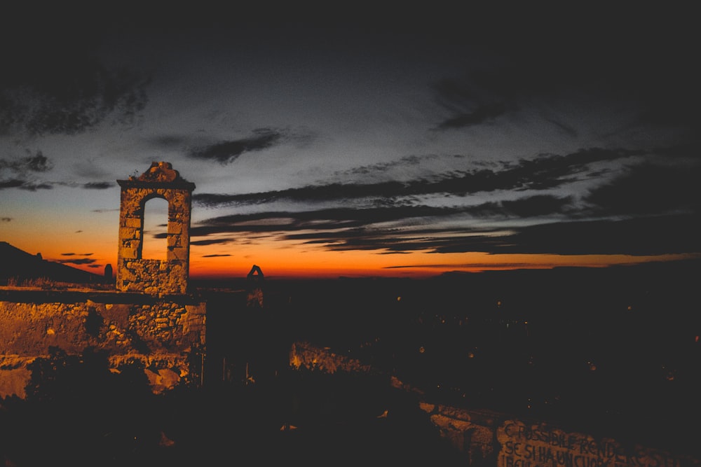 a clock tower sitting on top of a cliff under a cloudy sky