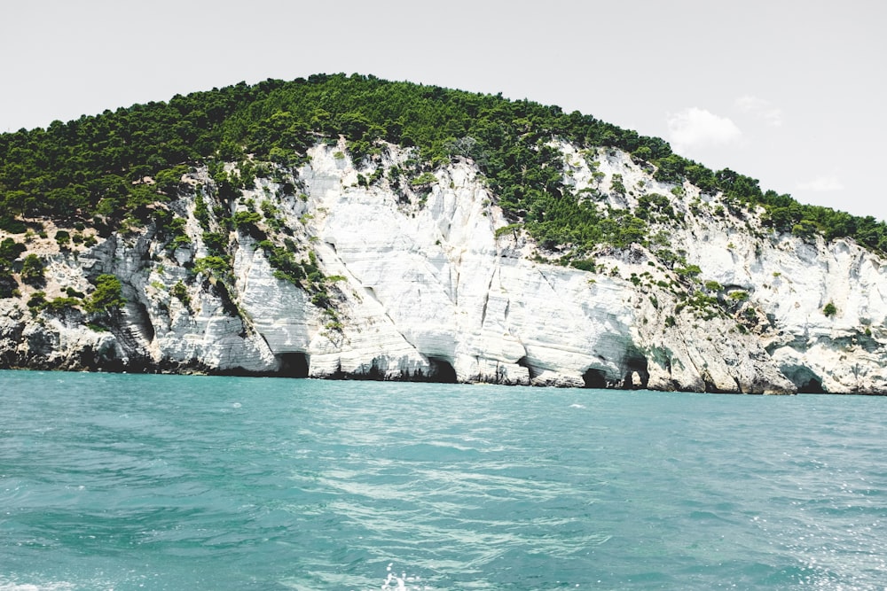 green and white mountain and body of water