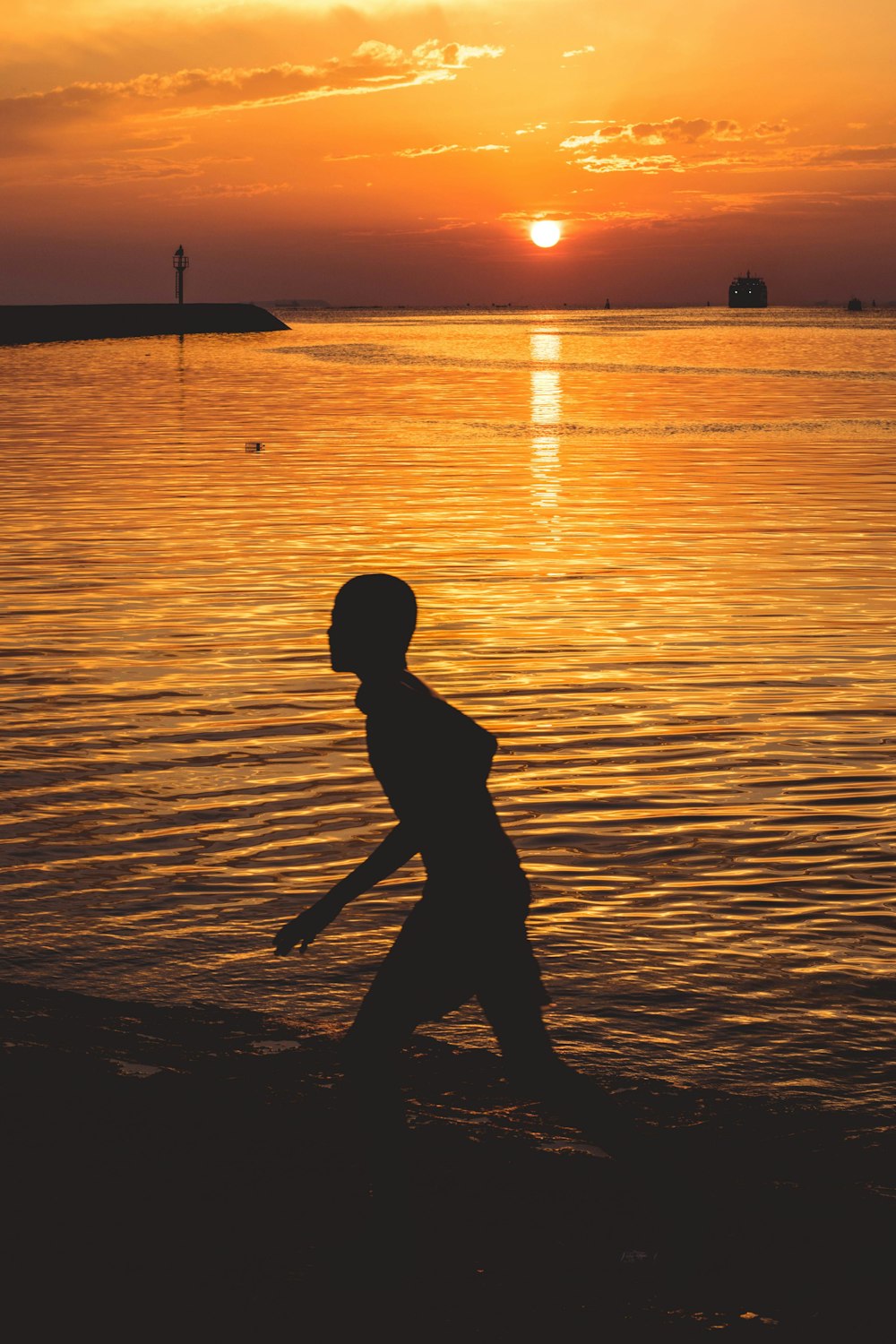 Silhouette einer Person am Meeresufer während des Sonnenuntergangs