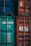 Two shipping containers, one with a teal color and identification numbers, and the other in faded red with a logo. Both containers have metallic structures and locks, indicating industrial use.