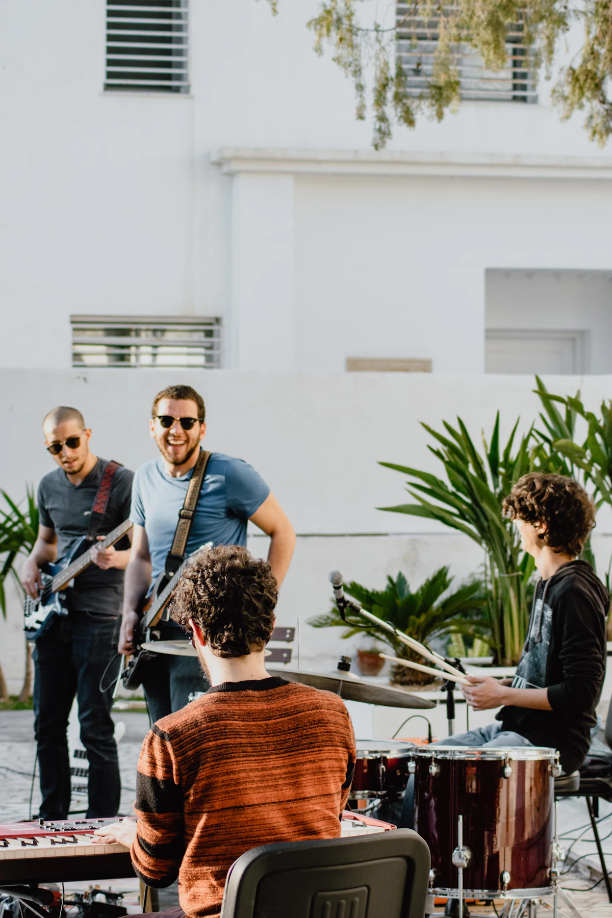 Young band members playing outdoors, laughing.