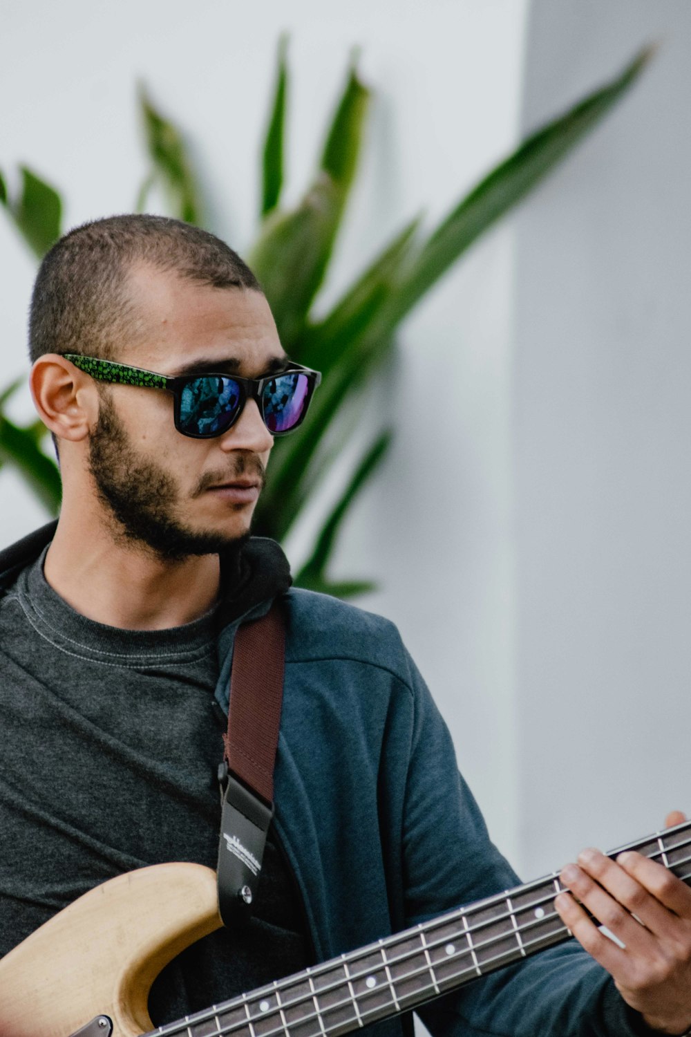 man wearing blue full-zip jacket holding brown electric base guitar