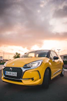 A modern yellow car parked against a clean white and blue background.