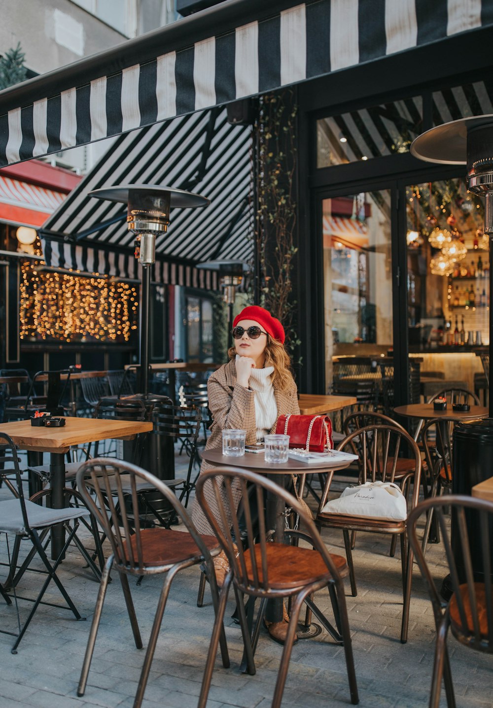 a woman sitting at a table outside of a restaurant