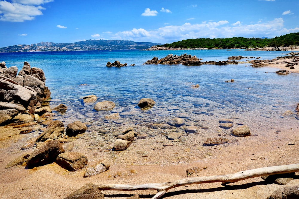 rocks on body of water across mountain during daytime