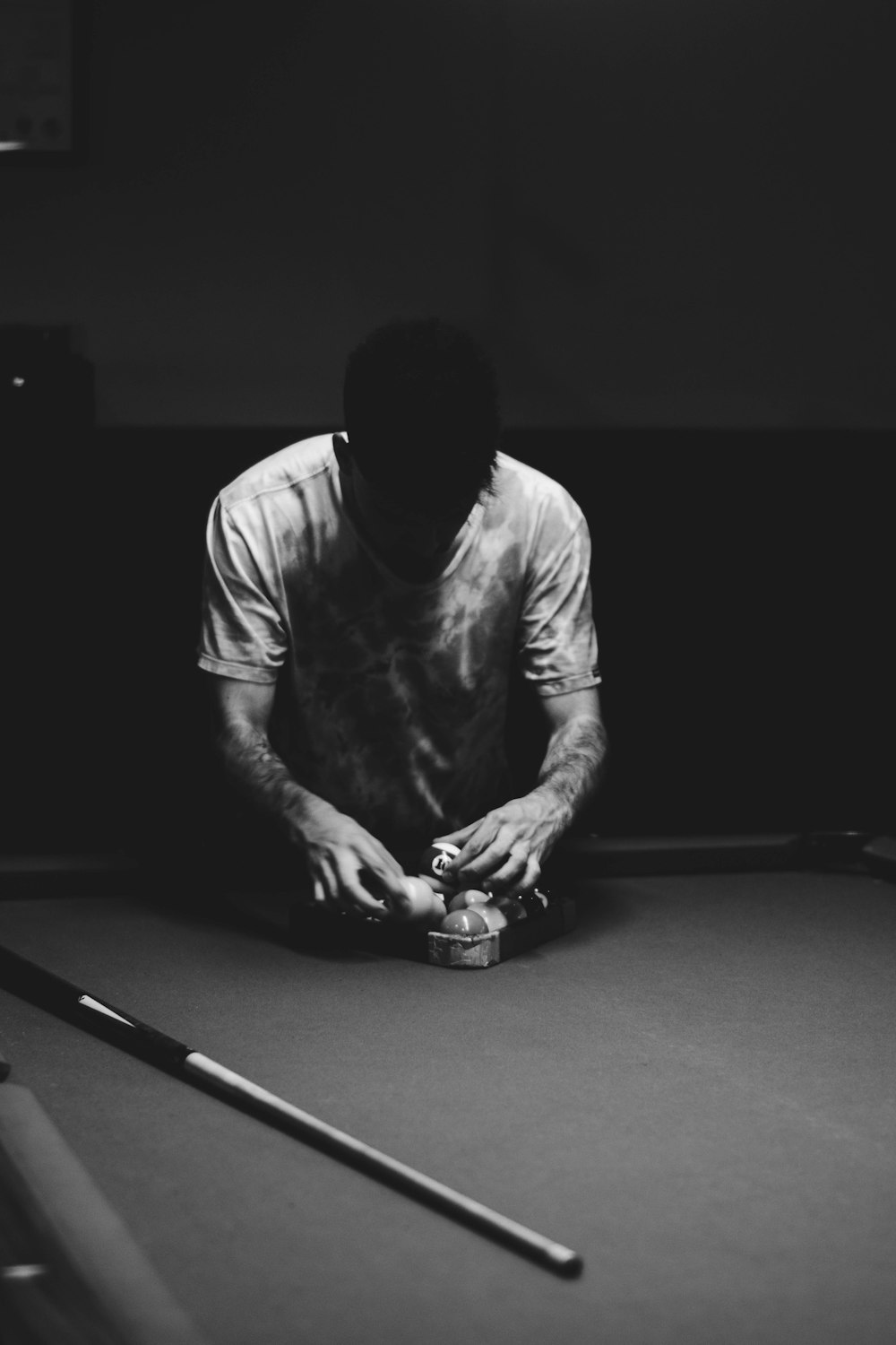 grayscale photo of man wearing shirt holding billiard balls on billiard table