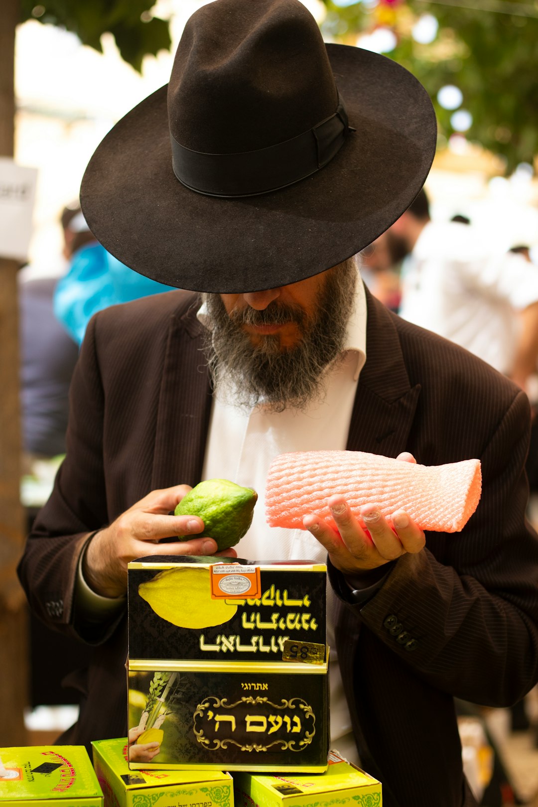 man wearing black hat holding green fruit