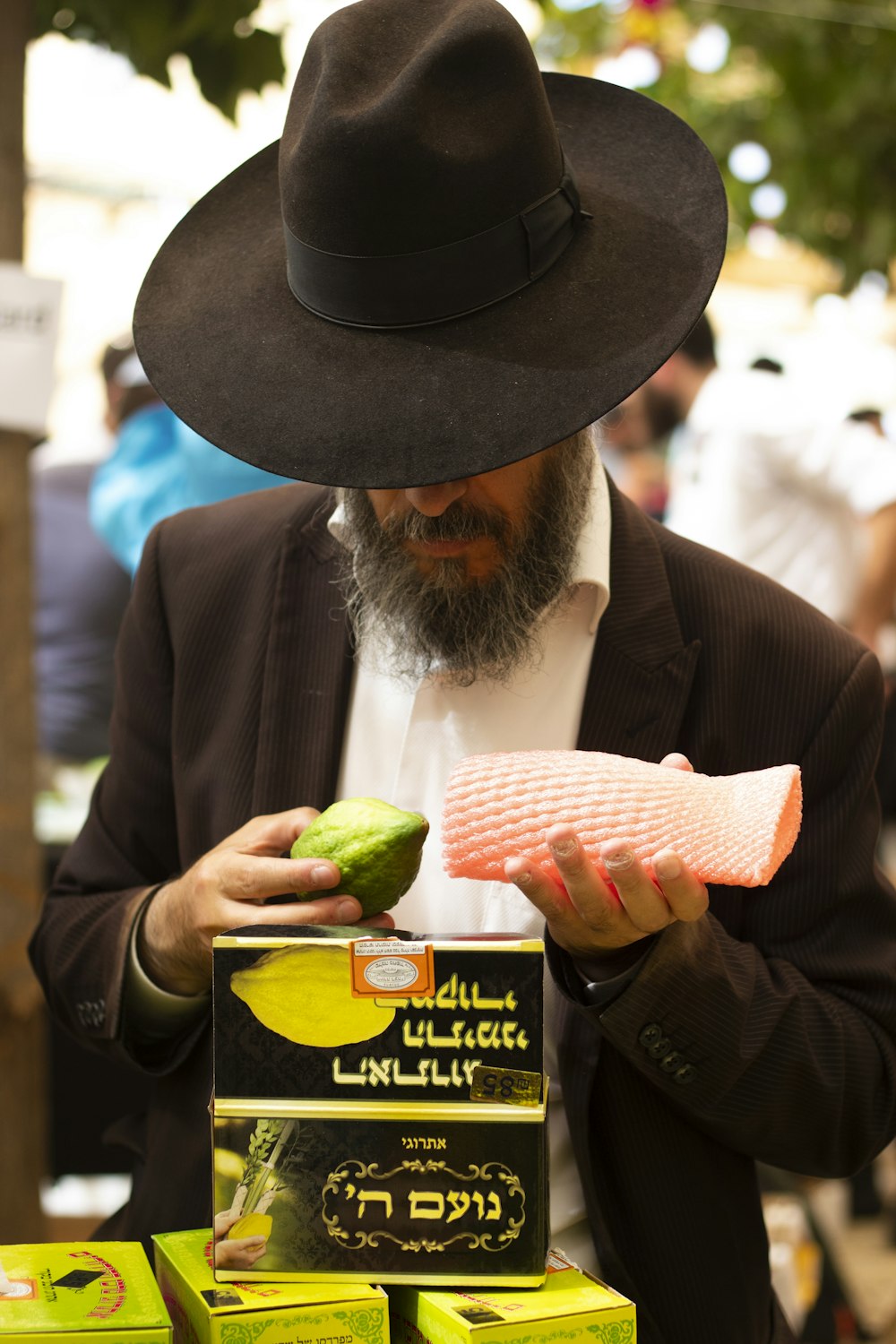 man wearing black hat holding green fruit