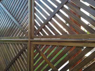A sleek modern fence with horizontal wooden slats framing a lush garden.