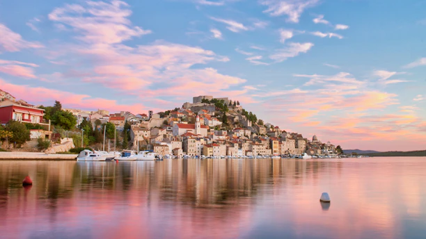 Panoramic view of Kotor's old town with its medieval walls and bay at sunset.