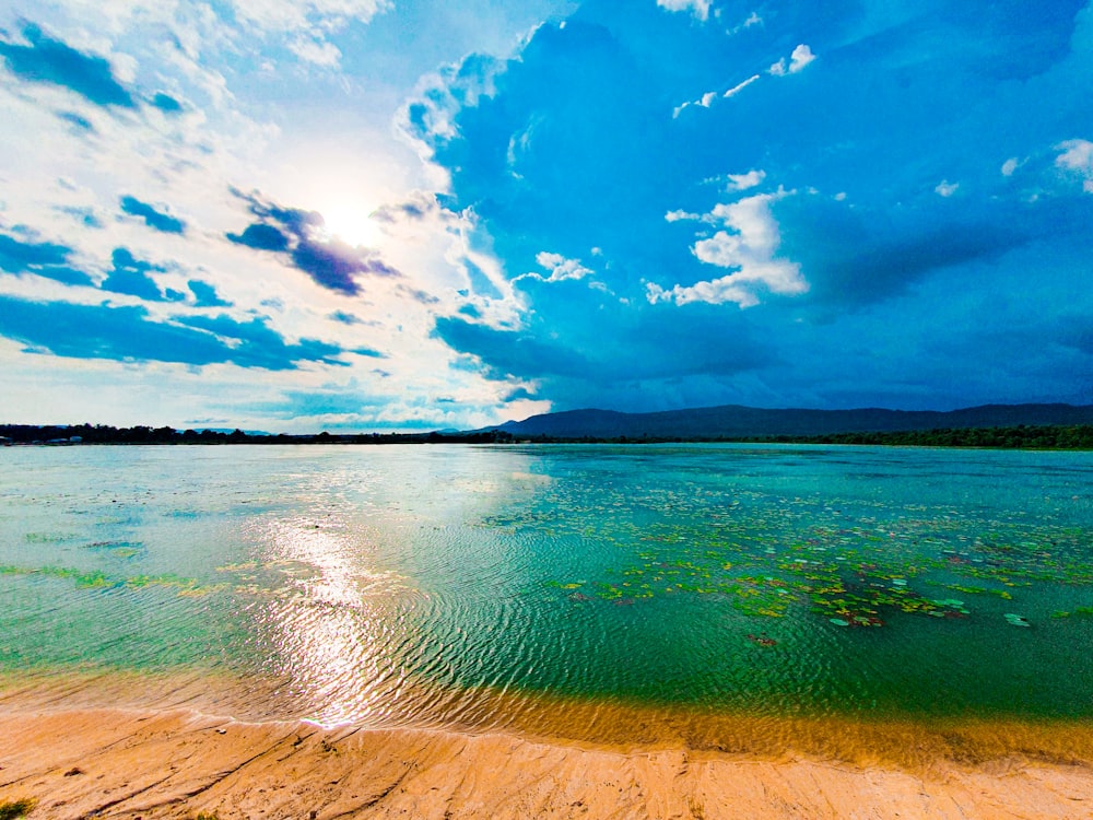 a body of water sitting under a cloudy blue sky
