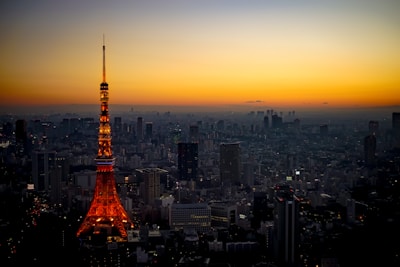A modern outdoor tower light illuminating a cityscape at dusk.