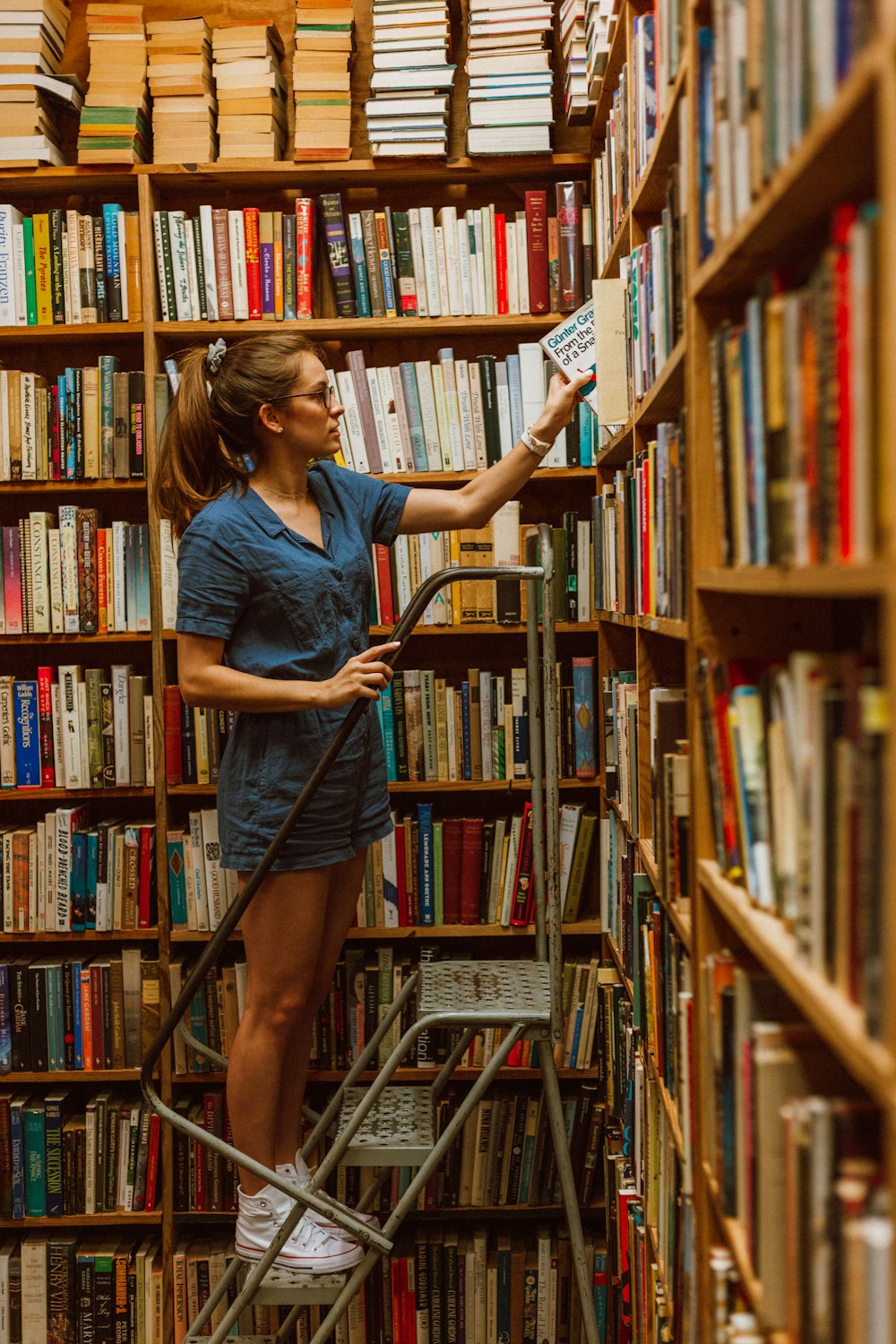 woman steps on ladder while holding book