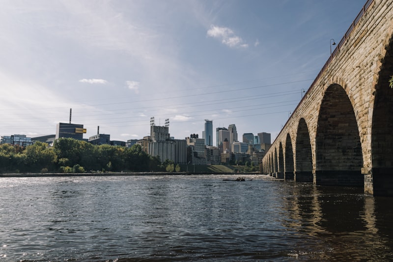 The stone arches of the Stone Arch Bridge stretching across the Mississippi River toward the Minneapolis skyline