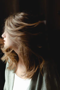 Close-up of a woman with shiny, healthy hair flowing naturally in soft light.