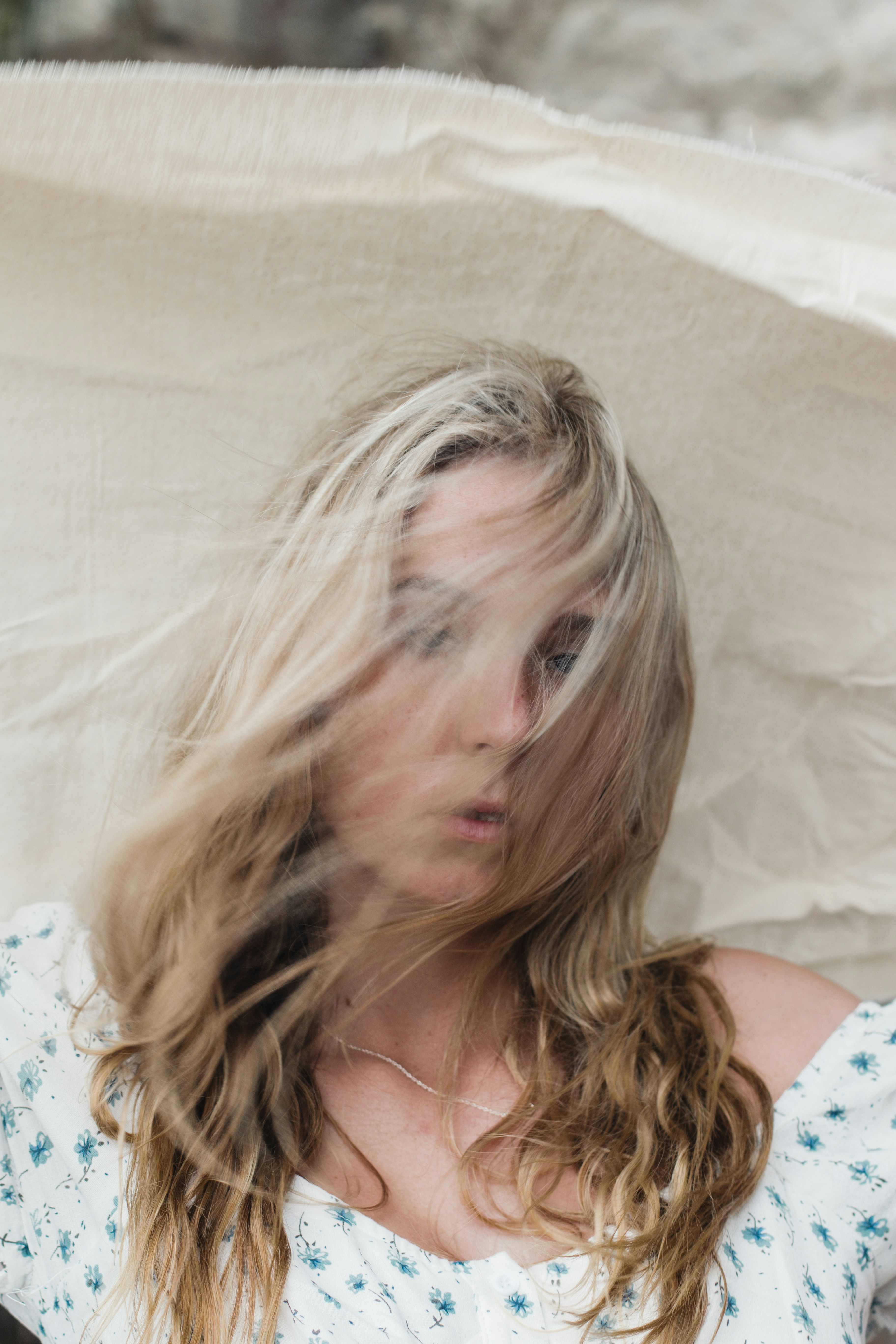 Wind and hair in face, holding fabric in the wind