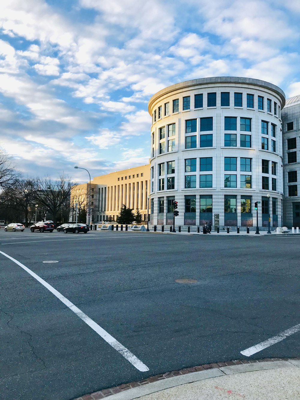 people walking on pathway near buildings and different vehicles on road under white and blue sky during daytime