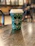 Photo of smiling café owner holding disposable cups from Ecoviva in a bustling coffee shop.