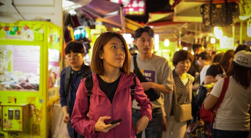 A warm snapshot of a traveler using Curateasy on their phone amidst a bustling local market.