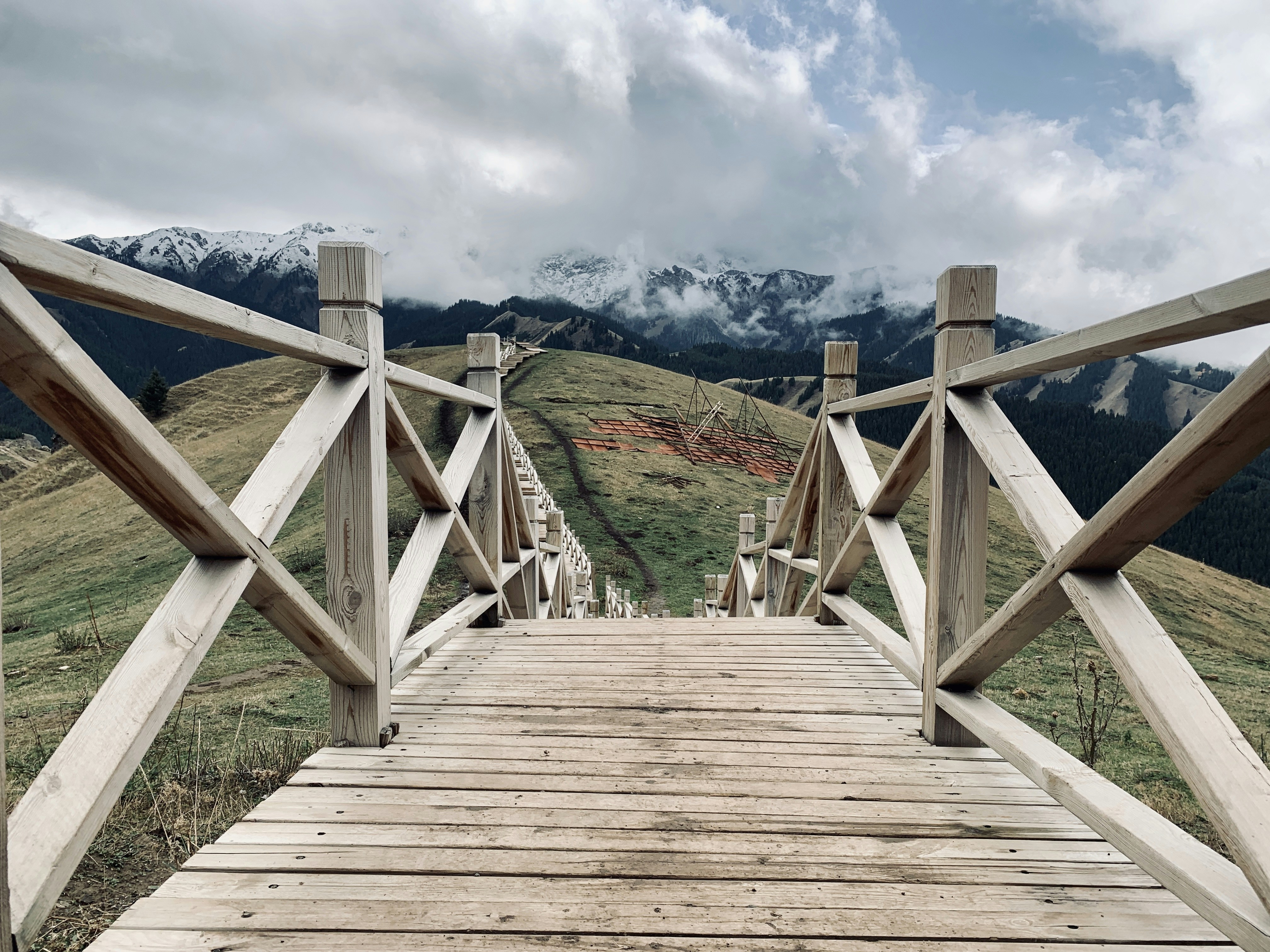 brown wooden dock near green field viewing mountain under white and blue sky during daytime